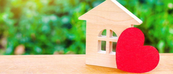 Close up image of a wooden heart and house on table.